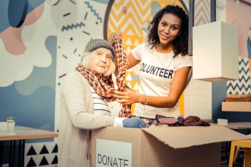 try-it-pleasant-afro-american-woman-smiling-while-helping-homeless-woman-wear-scarf